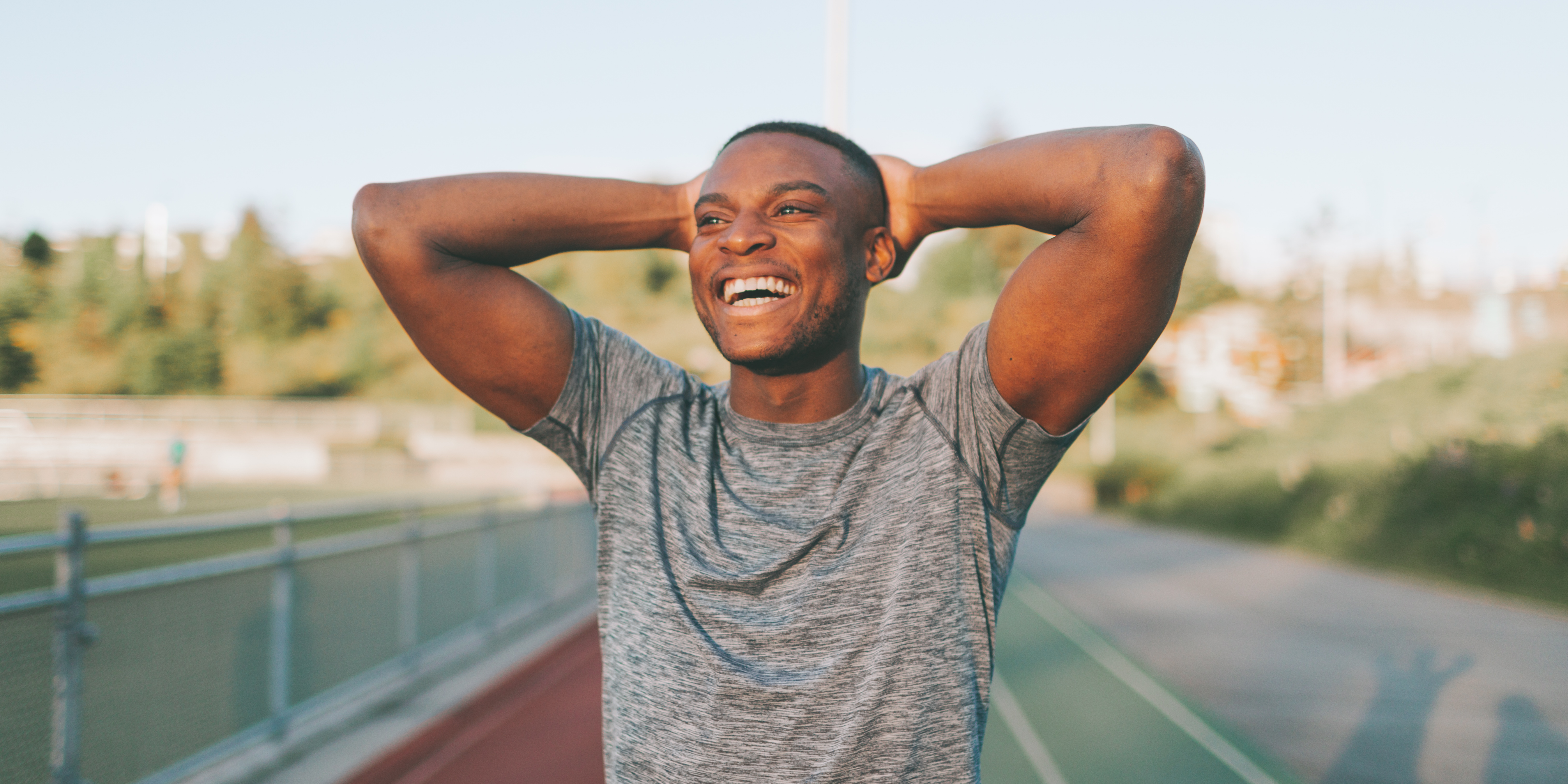 Man with his hands behind his head smiling