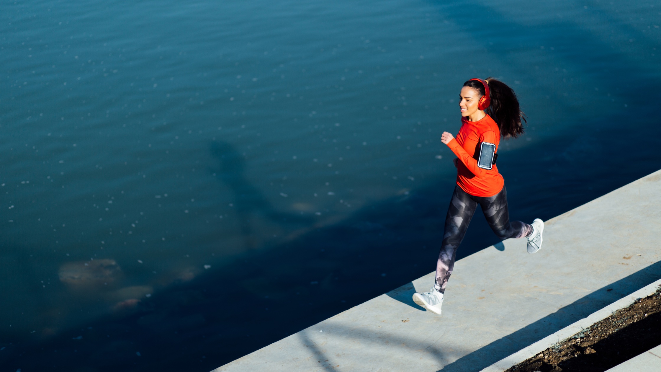 A woman running across a narrow bridge over shark infested waters