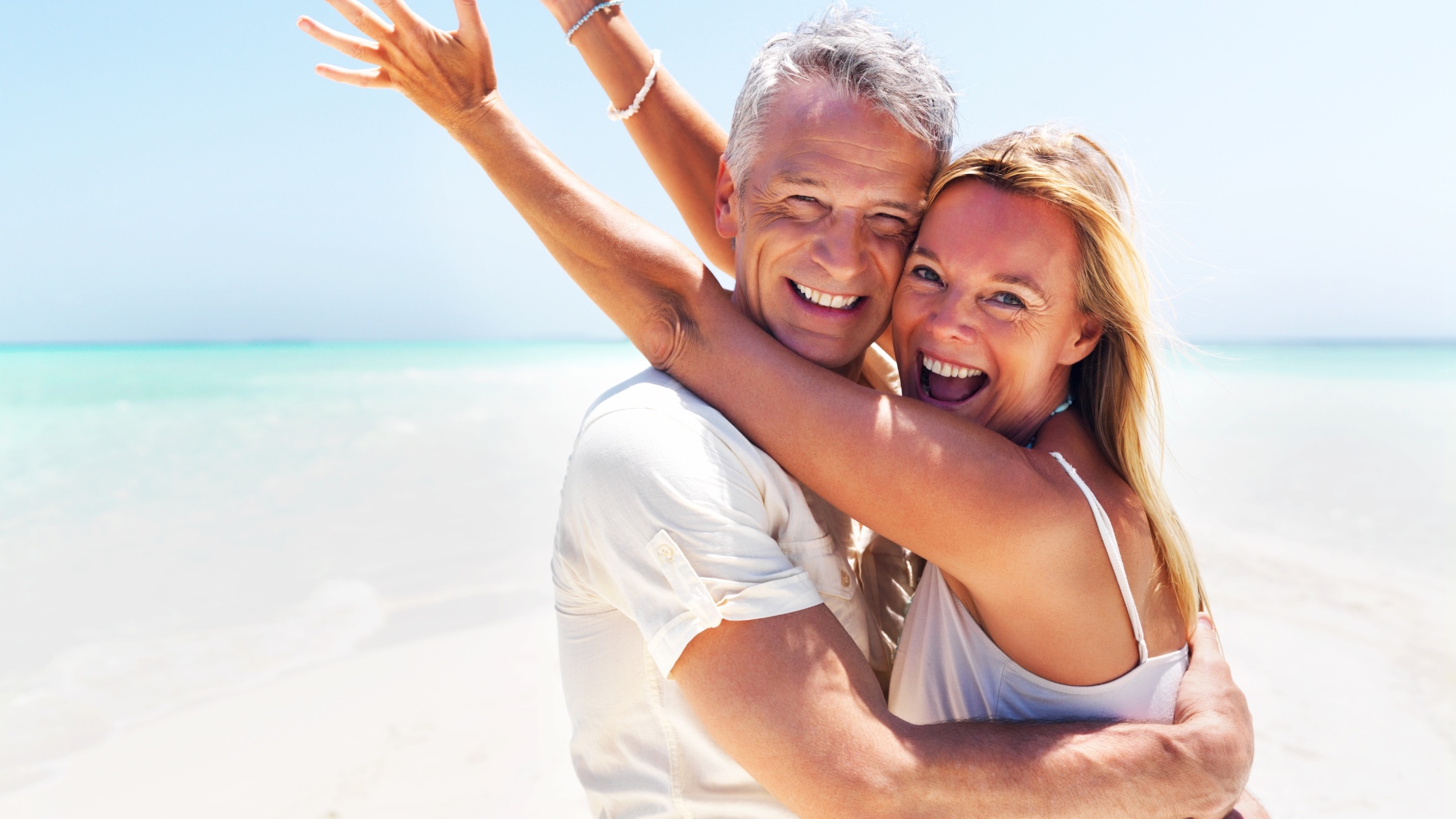 A man and woman embracing each other on the beach